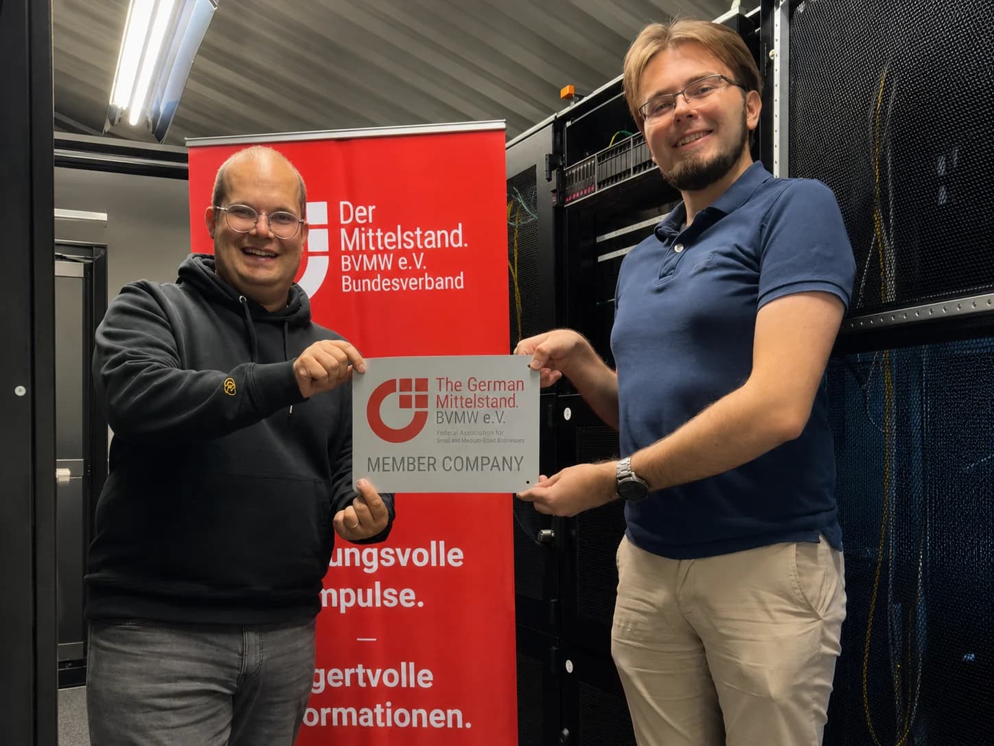Nico Freitag und Kevin Kröger mit dem BVMW-Mitgliedszeichen im Serverraum von sudo/PORT